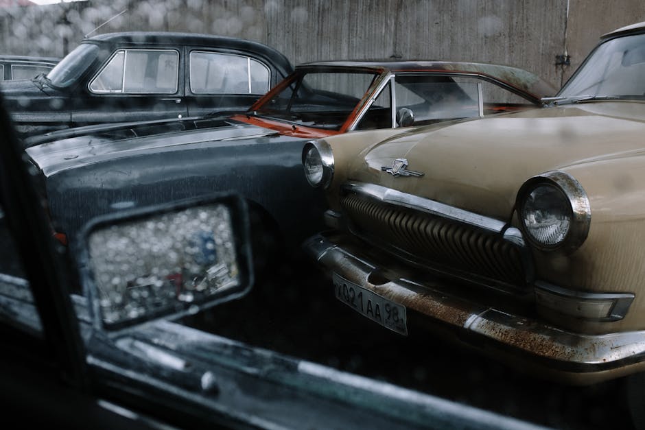 Vintage cars parked in the rain, showcasing retro design and automotive history.